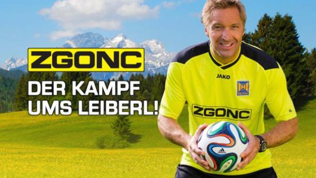 Ein Mann im Sporttrikot hält einen Fußball in einer ländlichen Umgebung.
