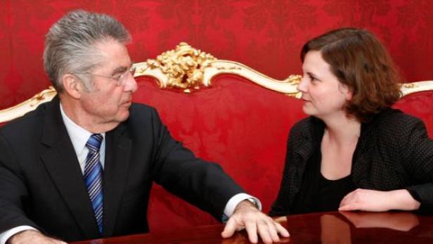 Ein Mann im Anzug und eine Frau sitzen an einem Tisch und unterhalten sich.