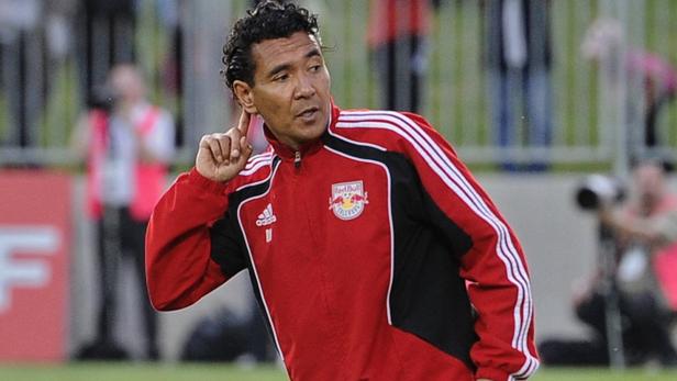 Ein Mann in einer roten Red Bull Salzburg Trainingsjacke berührt sein Ohr.