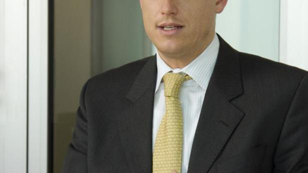 Ein Mann im Anzug mit gelber Krawatte gestikuliert mit den Händen.