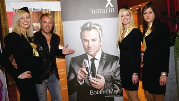 Männer posieren mit Hostessen vor einem „Botarin Men“-Werbebanner.