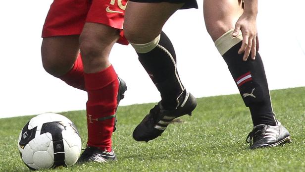 Fußballspieler kämpfen um den Ball auf einem grünen Rasen.