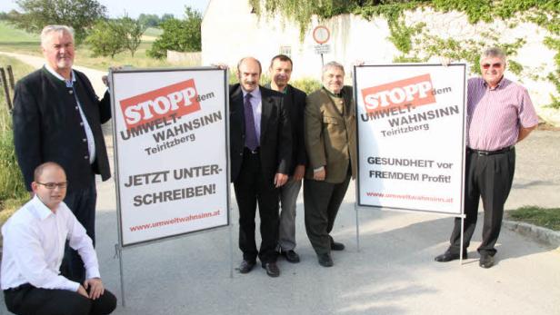Eine Gruppe von Personen posiert mit Schildern, die zum Stopp des „Umwelt-Wahnsinn“ in Teiritzberg aufrufen.