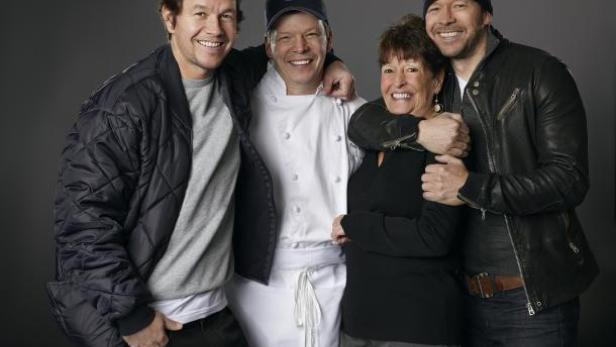 Mark und Donnie Wahlberg posieren mit ihrer Mutter und einem Koch.