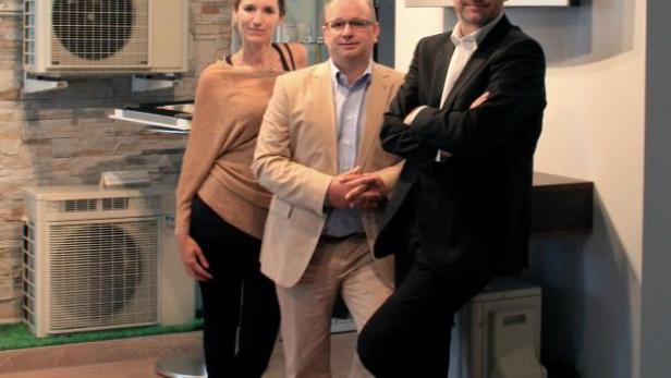 Drei Personen posieren vor einer Wand mit Daikin-Klimaanlagen.