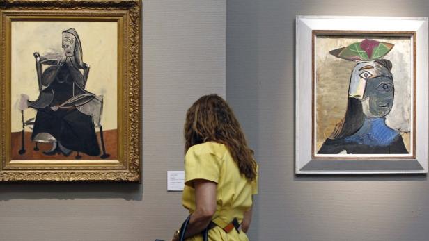 Eine Frau betrachtet zwei Gemälde von Pablo Picasso in einer Kunstgalerie.