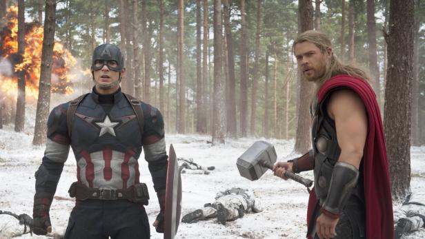 Captain America und Thor stehen in einem verschneiten Wald, im Hintergrund eine Explosion.