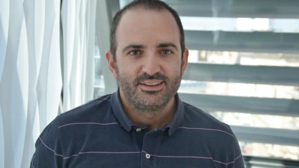 Ein Mann mit Bart und blauem Poloshirt blickt in die Kamera.