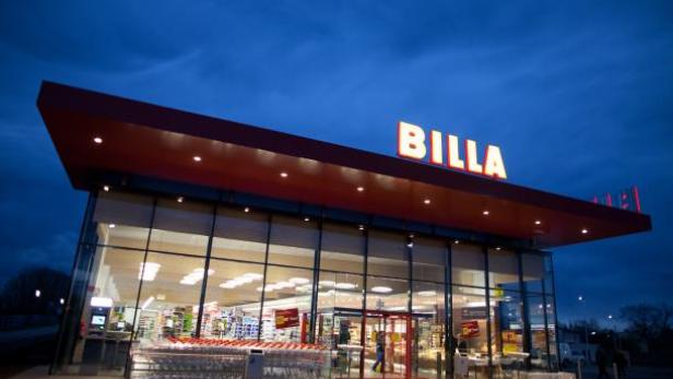Ein Billa-Supermarkt bei Dämmerung mit Einkaufswagen vor dem Eingang.