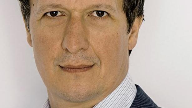 Ein Mann mit dunklem, gewelltem Haar trägt ein Hemd und einen Anzug.