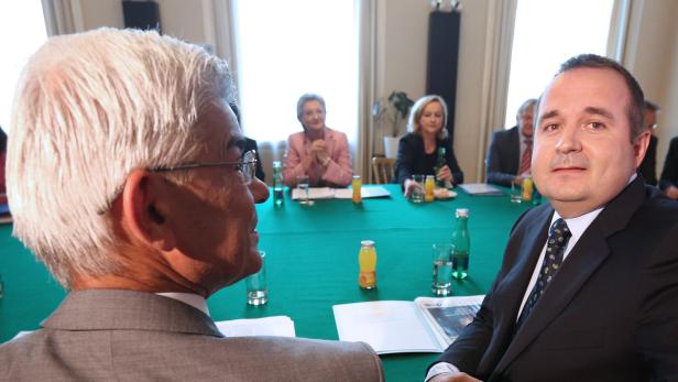 Mehrere Personen sitzen an einem Tisch mit grüner Tischdecke.