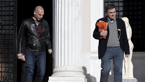 Zwei Männer stehen vor einem Gebäude mit Säulen und einer Statue.