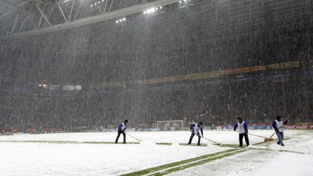 Mitarbeiter räumen während eines starken Schneefalls den Schnee von einem Fußballfeld.