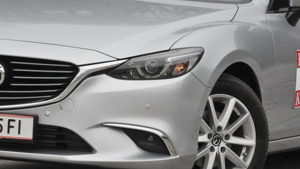Die Frontpartie eines silbernen Mazda mit markantem Kühlergrill und Scheinwerfern.