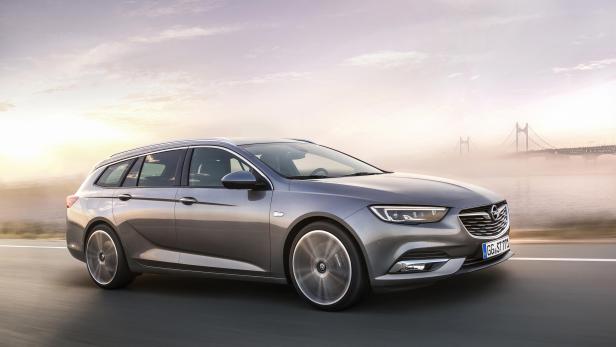 Ein grauer Opel Insignia Kombi fährt auf einer Straße entlang des Wassers.