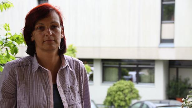 Eine Frau mit roten Haaren steht vor einem Gebäude.