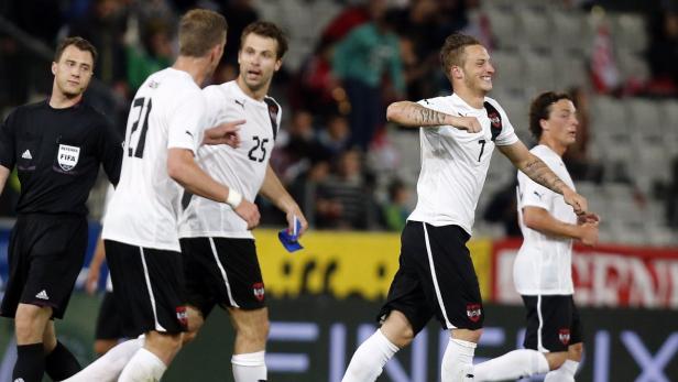 Ein österreichischer Fußballspieler jubelt mit seinen Teamkollegen und einem Schiedsrichter.