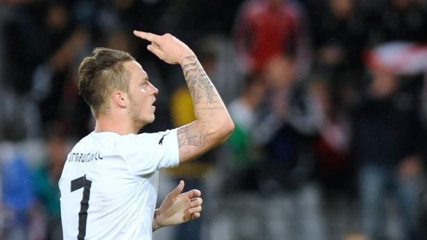 Ein Fußballspieler mit Tätowierungen feiert ein Tor.