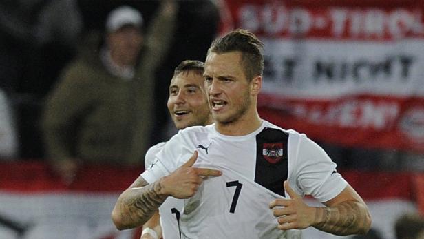 Ein österreichischer Fußballspieler zeigt auf sein Trikot mit der Nummer 7.