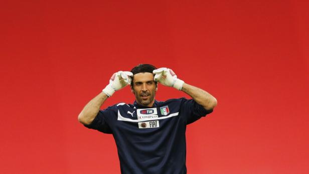 Gianluigi Buffon, italienischer Torwart, mit Handschuhen vor einem roten Hintergrund.