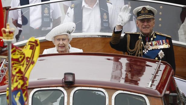 Königin Elisabeth II. und Prinz Philip winken von einem Boot aus.