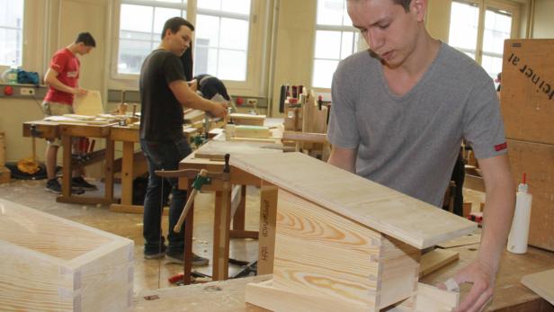 Ein junger Mann arbeitet in einer Werkstatt an einem Holzprojekt.