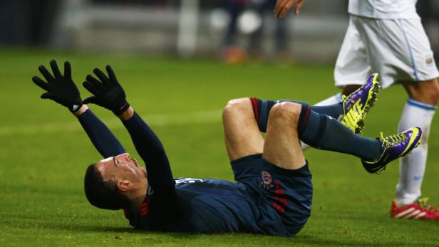 Ein Fußballspieler liegt mit erhobenen Händen auf dem Rasen.