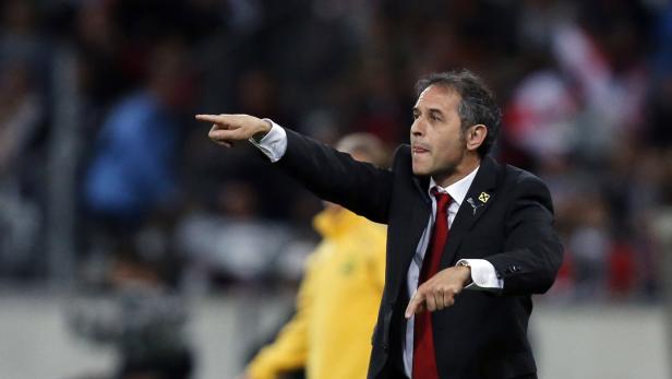 Ein Trainer in Anzug und Krawatte gestikuliert während eines Spiels.