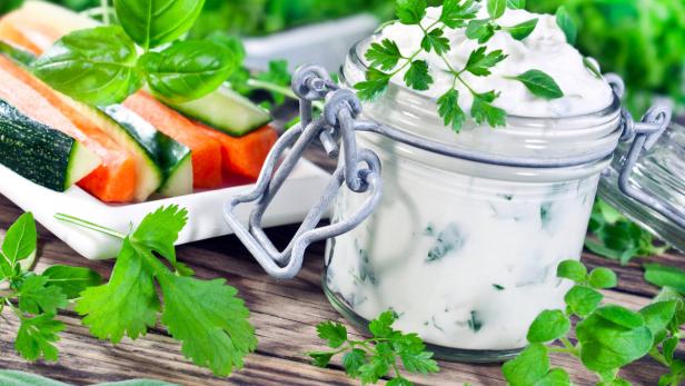 Gemüsesticks mit Kräuterdip in einem Glas auf einem Holztisch.