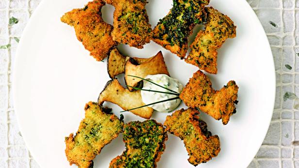 Ein Teller mit panierten Pilzen und einem Dip mit Kräutern.