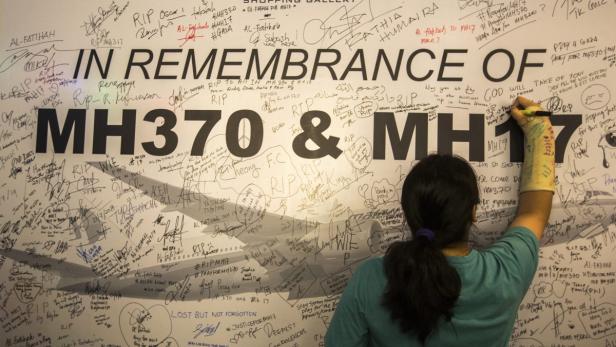 Eine Frau unterschreibt auf einer Gedenktafel für die Opfer der Flüge MH 17 und MH 370, der seit März mit 239 Menschen an Bord verschwunden ist.