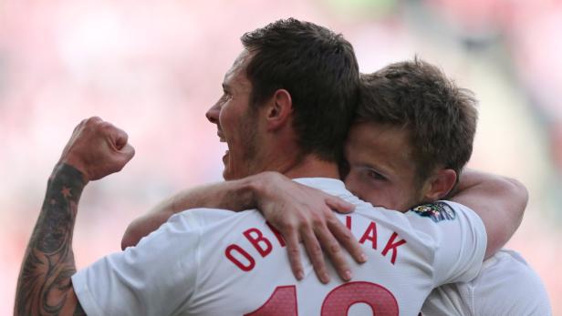 Zwei Fußballspieler umarmen sich freudig, einer mit Tätowierung am Arm.