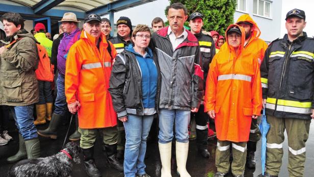 Eine Gruppe von Feuerwehrleuten in Regenkleidung steht im Freien.