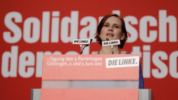 Eine Frau spricht am Rednerpult vor einem roten Hintergrund mit dem Schriftzug „Solidarisch“ für „Die Linke“.