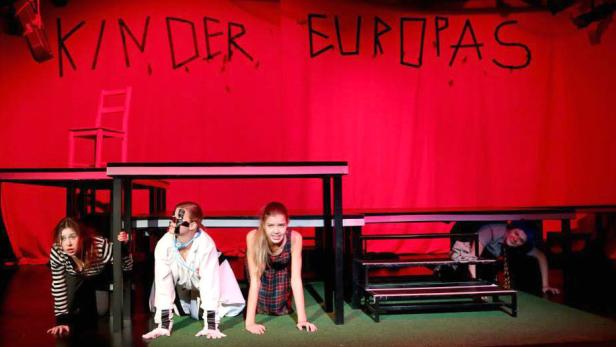 Eine Theaterszene mit dem Titel „Kinder Europas“ im Hintergrund.