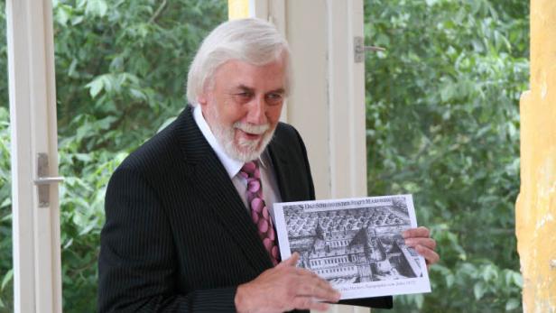 Ein Mann im Anzug präsentiert eine historische Abbildung von Schloss Marchegg.