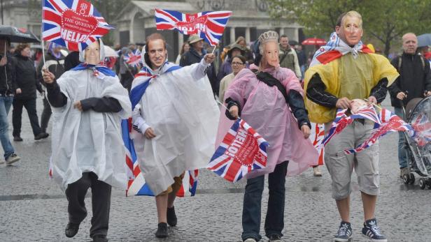 Menschen mit Masken der königlichen Familie und Union-Jack-Flaggen feiern ein Jubiläum.