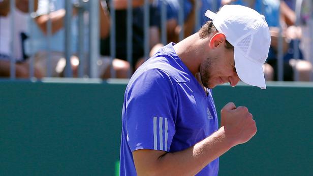 Ein Tennisspieler in blauem Hemd und weißer Kappe ballt die Faust.
