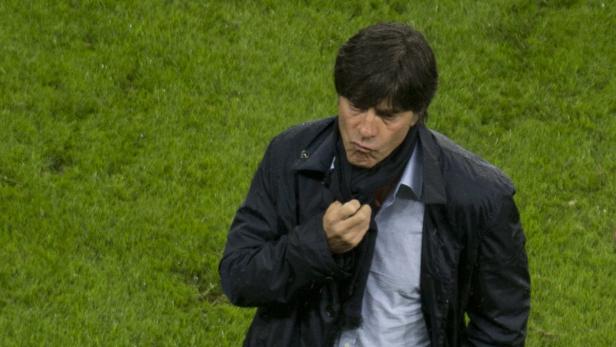 Joachim Löw steht auf einem Rasenplatz und nestelt an seinem Schal.