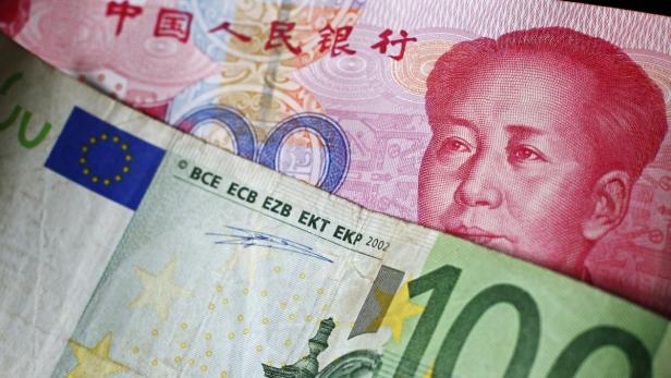 Eine 100-Euro-Banknote liegt vor einer chinesischen Yuan-Banknote.