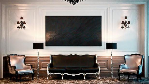 Ein elegant eingerichteter Raum mit einem Sofa, zwei Sesseln und einem großen Gemälde.