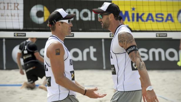 Zwei Beachvolleyballspieler unterhalten sich am Netz.