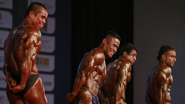 Mehrere Bodybuilder posieren auf einer Bühne.