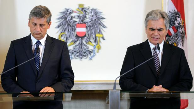 Zwei Männer in Anzügen stehen an einem Rednerpult vor dem österreichischen Wappen.