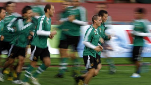 Eine Gruppe von Fußballspielern joggt auf einem grünen Rasen.