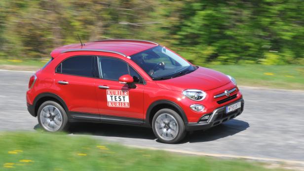 Ein roter Fiat 500X fährt auf einer Landstraße.