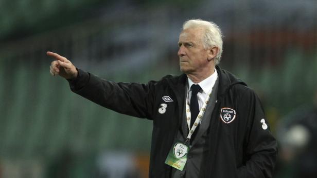 Ein älterer Mann in einer Jacke mit Irland-Logo zeigt mit dem Finger.