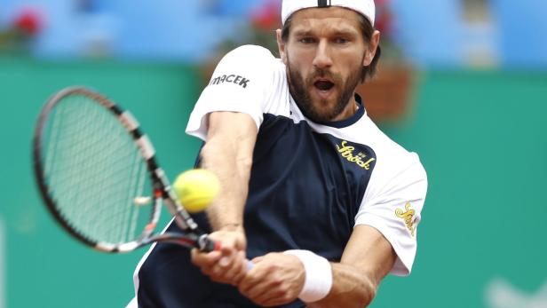 Ein Tennisspieler schlägt einen gelben Tennisball mit seinem Schläger.