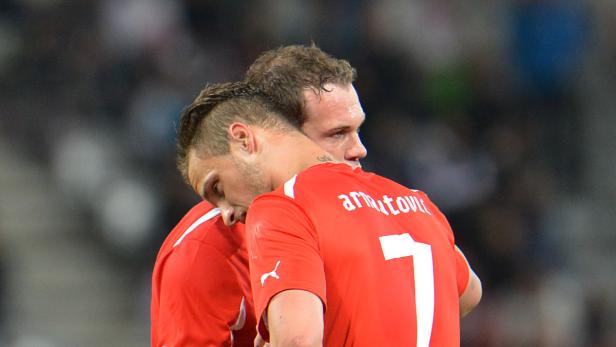 Zwei Fußballspieler in roten Trikots umarmen sich.