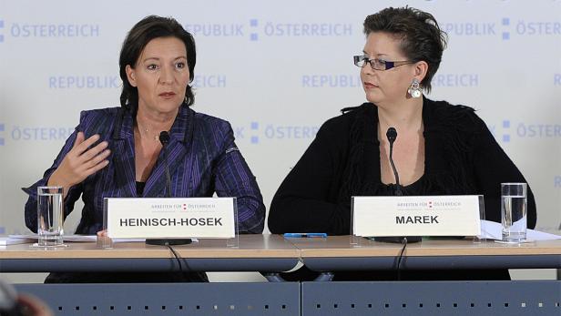Zwei Frauen, Heinisch-Hosek und Marek, sitzen an einem Tisch mit Namensschildern vor sich.